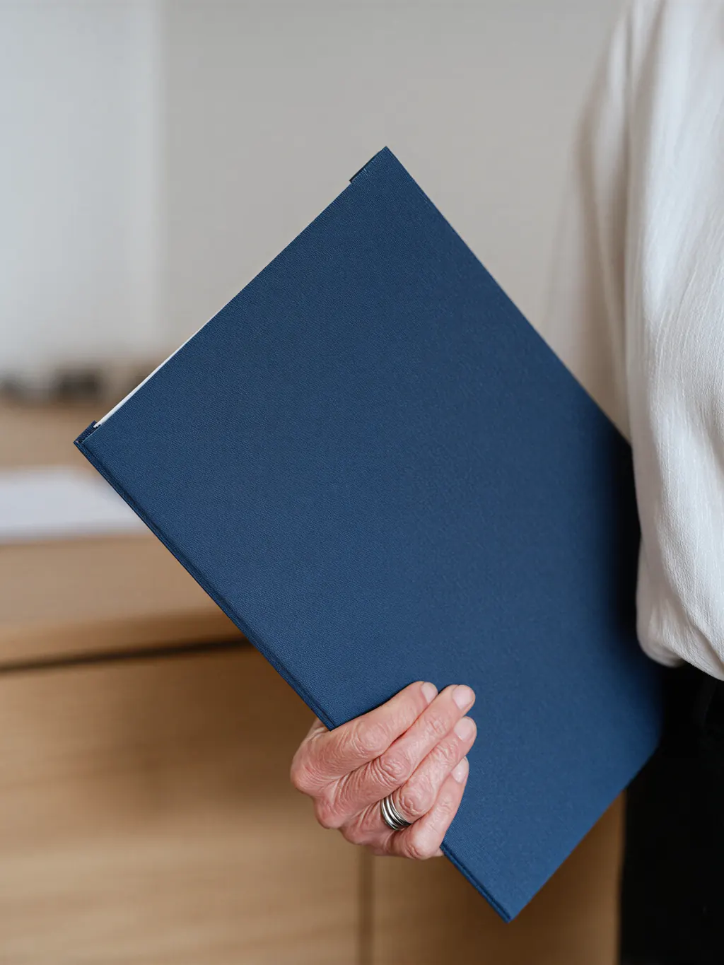 A person holding a navy document folder.